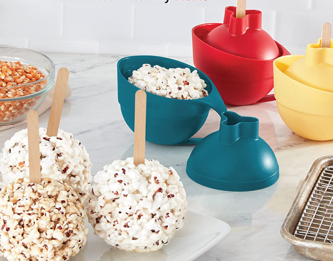 Popcorn balls with sticks on them next to the silicone containers 