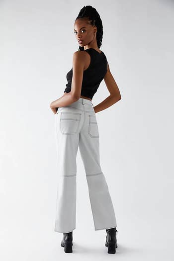 back of a model wearing stone-colored vegan leather pants with a black tank top