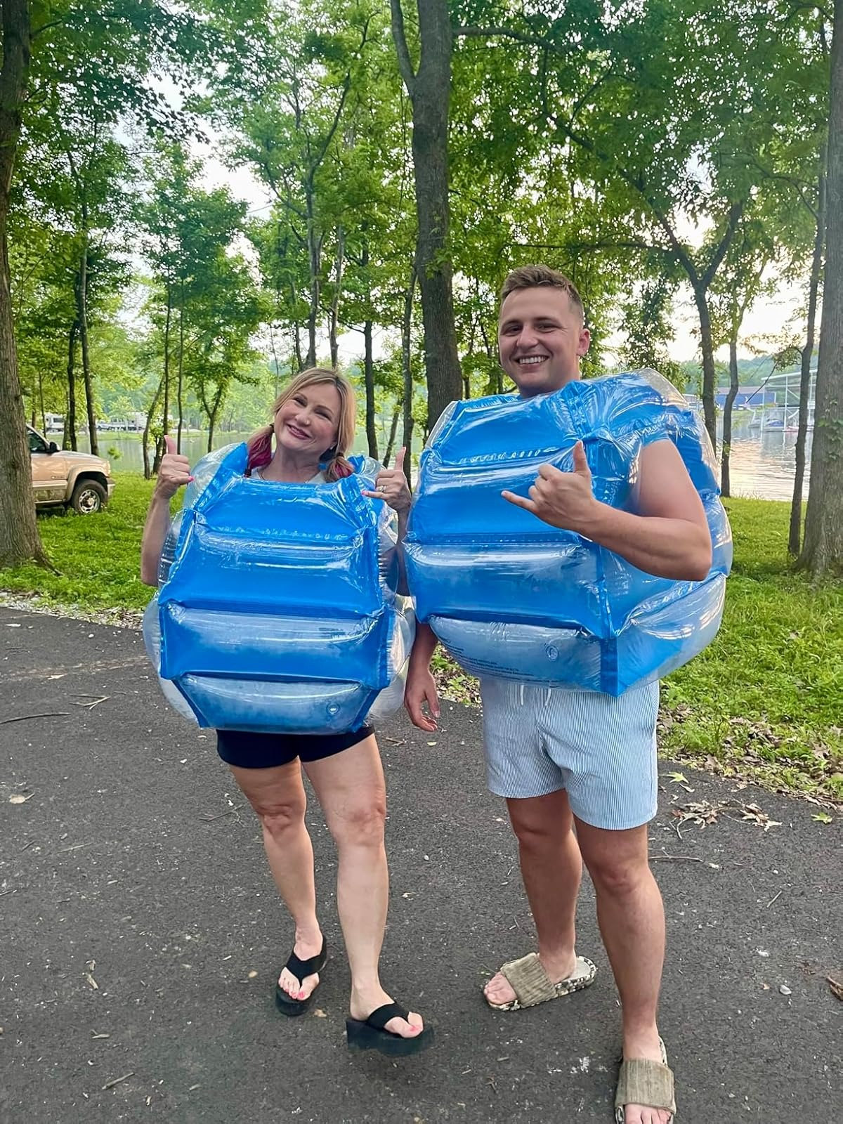Two radical   outdoors wearing inflatable bumper vests, smiling and posing playfully. Trees disposable   successful  the background. Casual summertime  attire