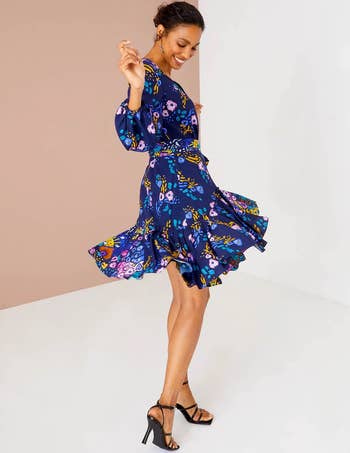 side view of model twirling in the blue floral dress
