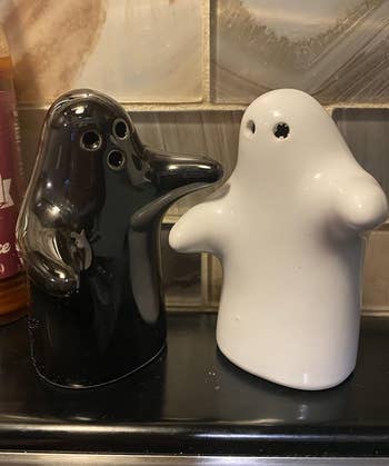 Black and achromatic  ghost-shaped brackish  and capsicum  shakers connected  a shelf
