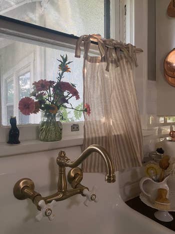 Wastafel dapur dengan vas faucet kuningan bunga di jendela
