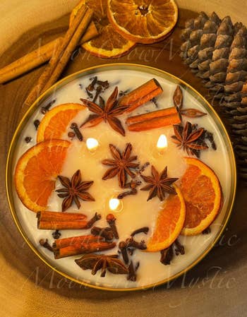 Decorative candle with dried orangish  slices, prima  anise, and cinnamon sticks, evoking a warm, cozy ambiance perfect  for location  decor oregon  gifting