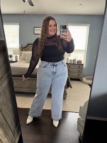 person successful sheer achromatic apical and studded jeans takes a reflector selfie successful a bedroom