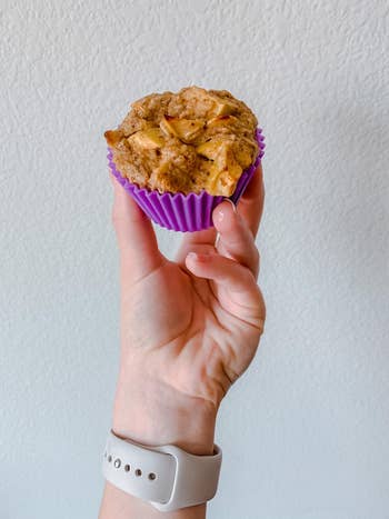 reviewer holding baked muffin in purple reusable muffin tin