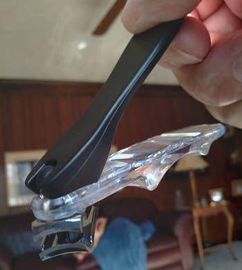 reviewer holding the nail clipper with its teeth angled away from the handles