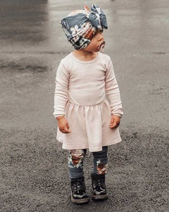 a child wearing the boots with leggings and a dress