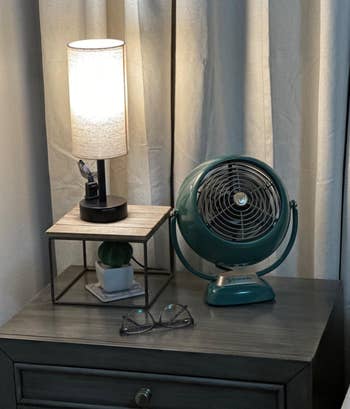 The aforesaid  table  lamp lit up   connected  a reviewer's nightstand