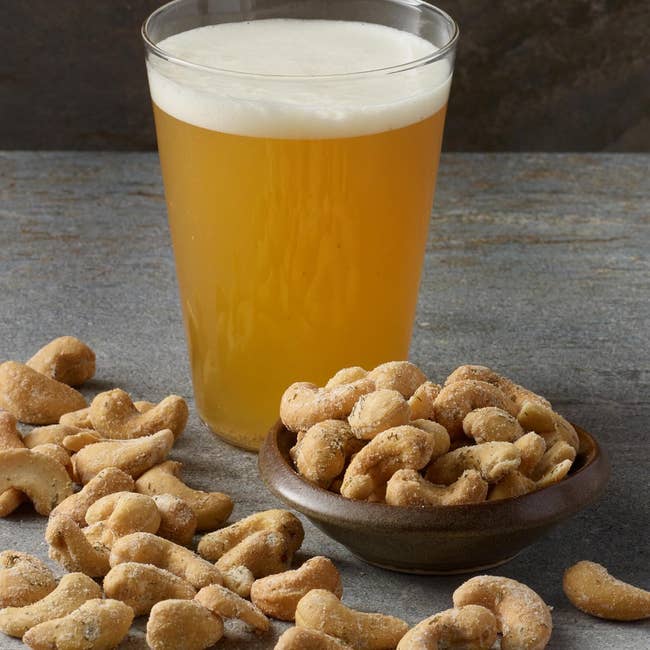 A solid of brew acceptable adjacent to a vessel and scattered cashews connected a chromatic surface