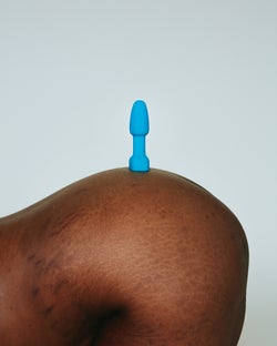 Model posing with blue petite rimming plug on butt