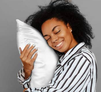 model rubbing their face on a white satin pillow