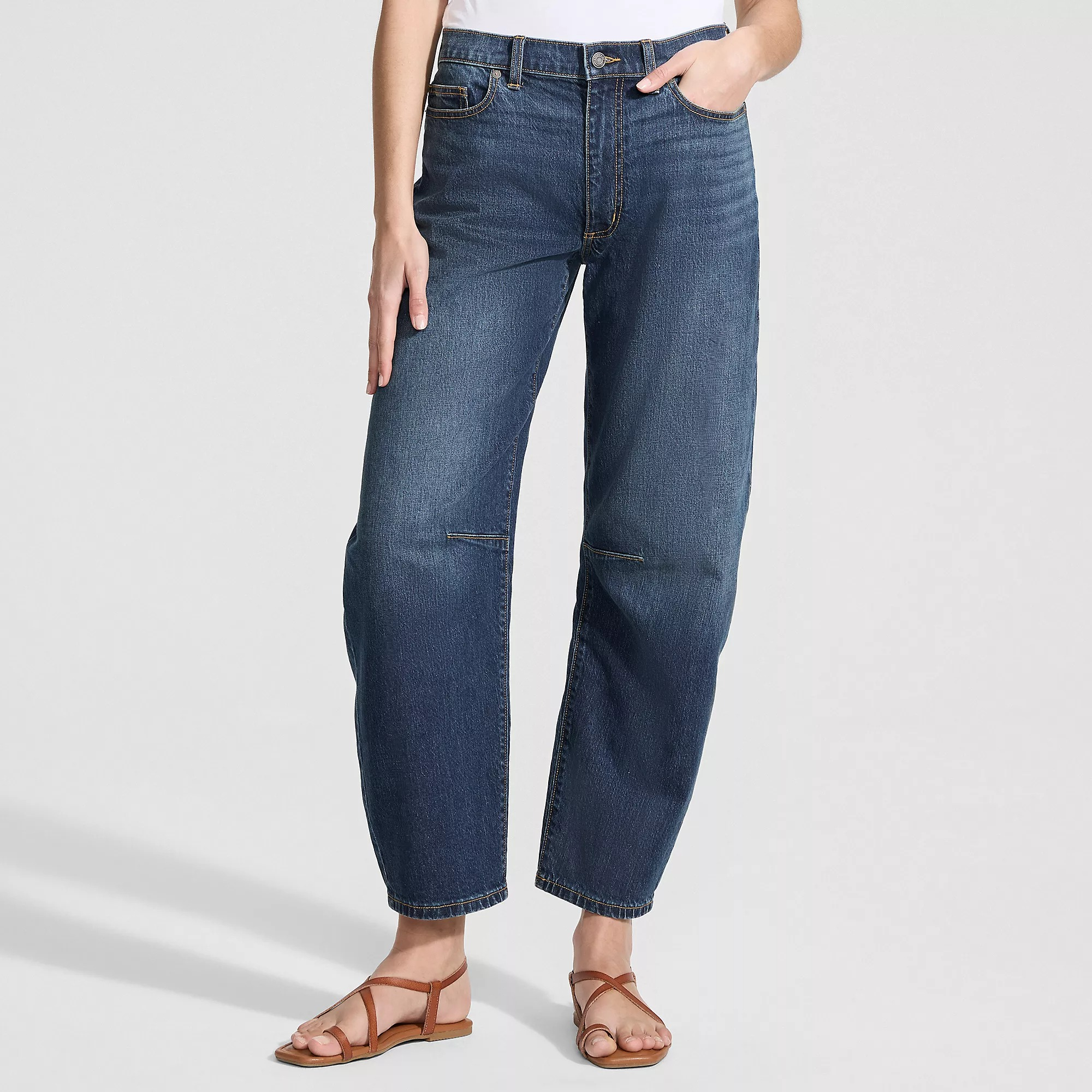 Person wearing relaxed-fit jeans and sandals, lasting  with 1  manus  successful  pocket. Casual outfit suitable for mundane  wear