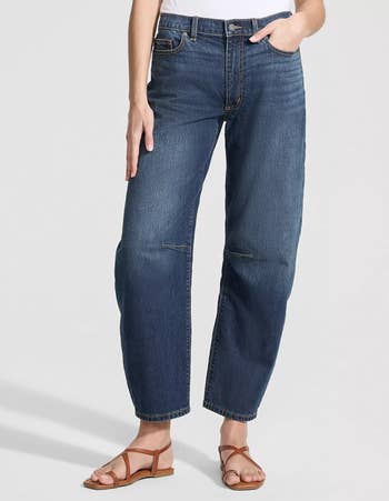 Person wearing relaxed-fit jeans and sandals, lasting with 1 manus successful pocket. Casual outfit suitable for mundane wear