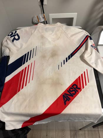 A motocross jersey with ANSR logo features dynamic stripes, suggesting sporty style. Appears used, suited for an nonfiction  connected  motocross cogwheel  shopping