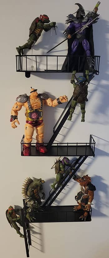 reviewer photo of the fire escape shelf hanging on a wall and holding assorted action figures