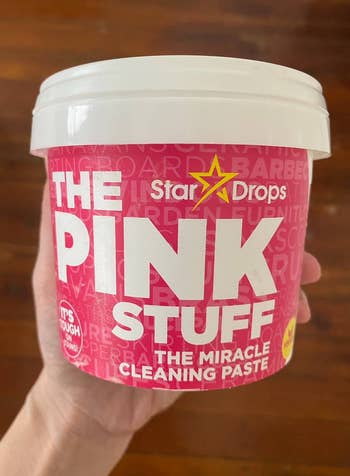 Hand holding a container of Star Drops The Pink Stuff, a miracle cleaning paste, useful for tough grime and stains