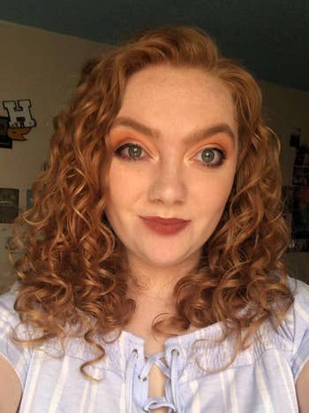 Reviewer in a blue and white top with red smooth curly hair