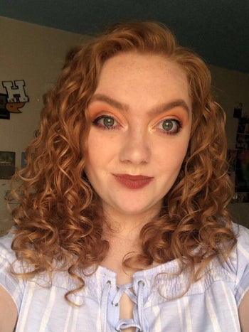Reviewer in a blue and white top with red smooth curly hair