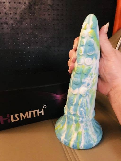 Reviewer holding blue and green tentacle dildo