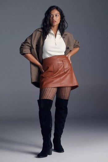 another model wearing black over-the-knee boots with stockings, a mini skirt, and a blazer