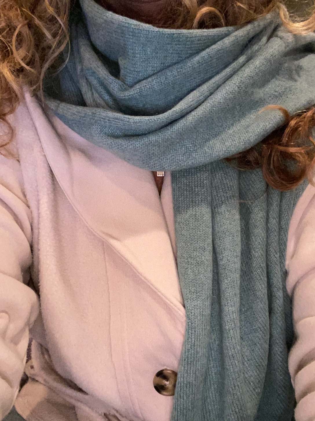 a reviewer wearing the scarf paired with a pink coat
