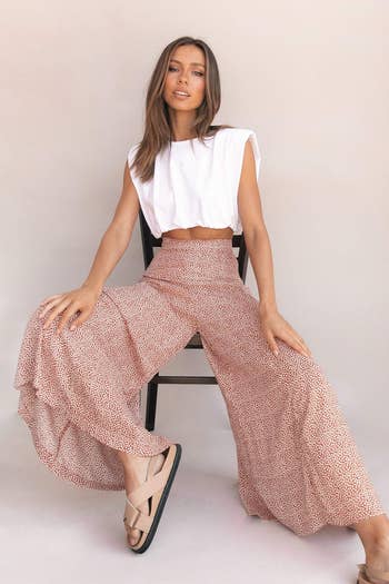 model seated on a chair in a white top and patterned flowing pants