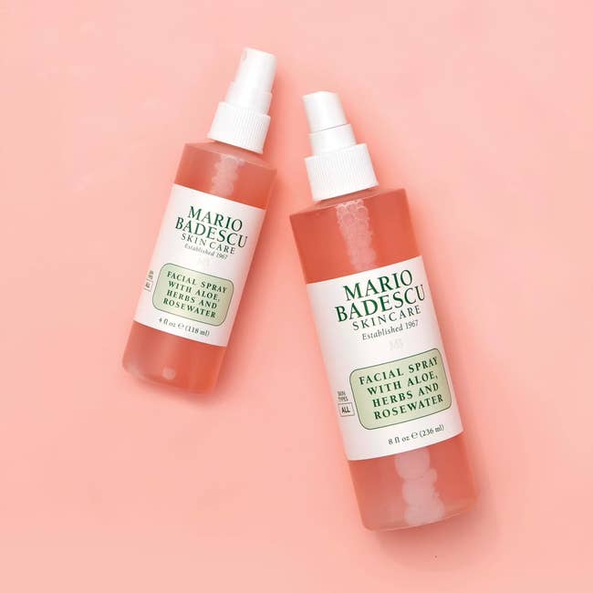 Two bottles of Mario Badescu Facial Spray with Aloe, Herbs, and Rosewater are lying connected  a level  surface