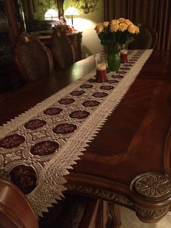 Elegant dining table with an intricate table runner and a bouquet of roses in a vase