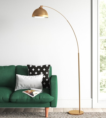 the arched gold lamp on an area rug next to a green couch