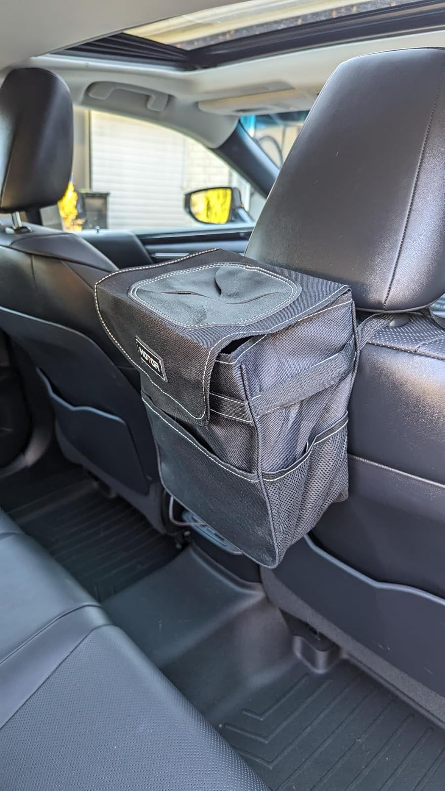 Back seat of a car showing a trash can 