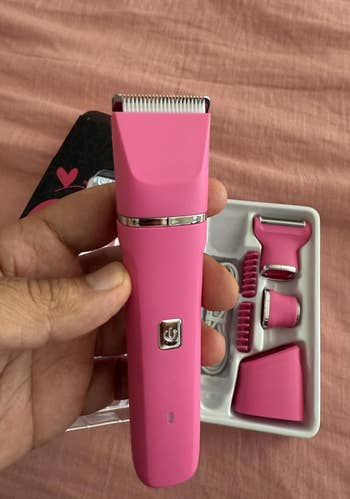 A manus  holds a pinkish  electrical  grooming kit with attachment pieces, suitable for idiosyncratic   attraction   shopping