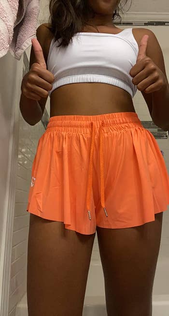 travel reviewer wearing the shorts in orange