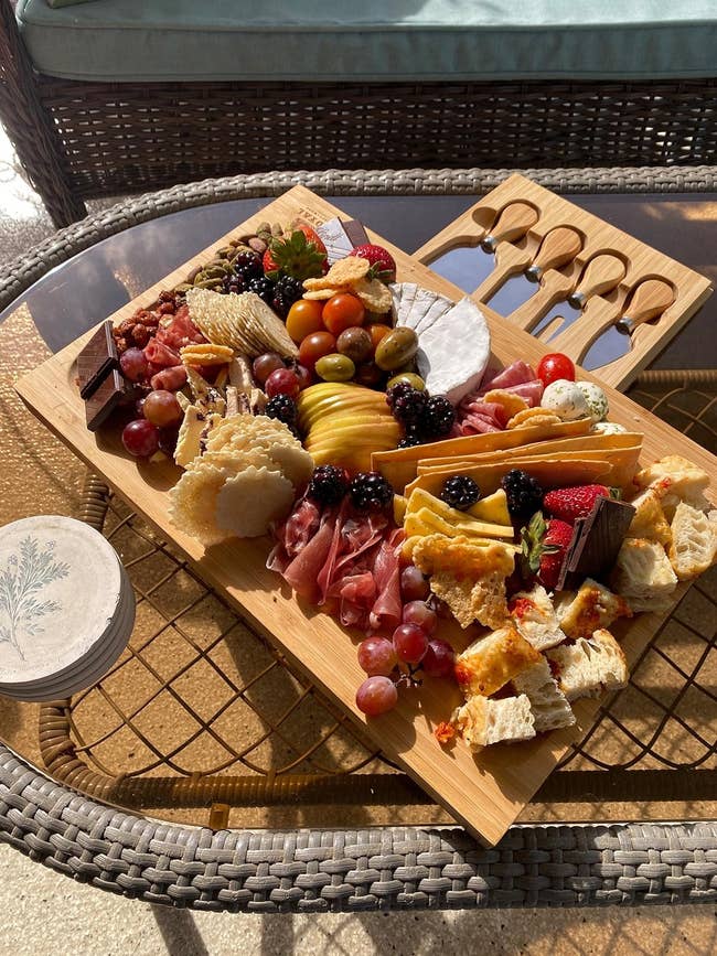 reviewer photo of meats, cheeses, fruits and crackers placed on charcuterie board showing the hidden tray holding knives
