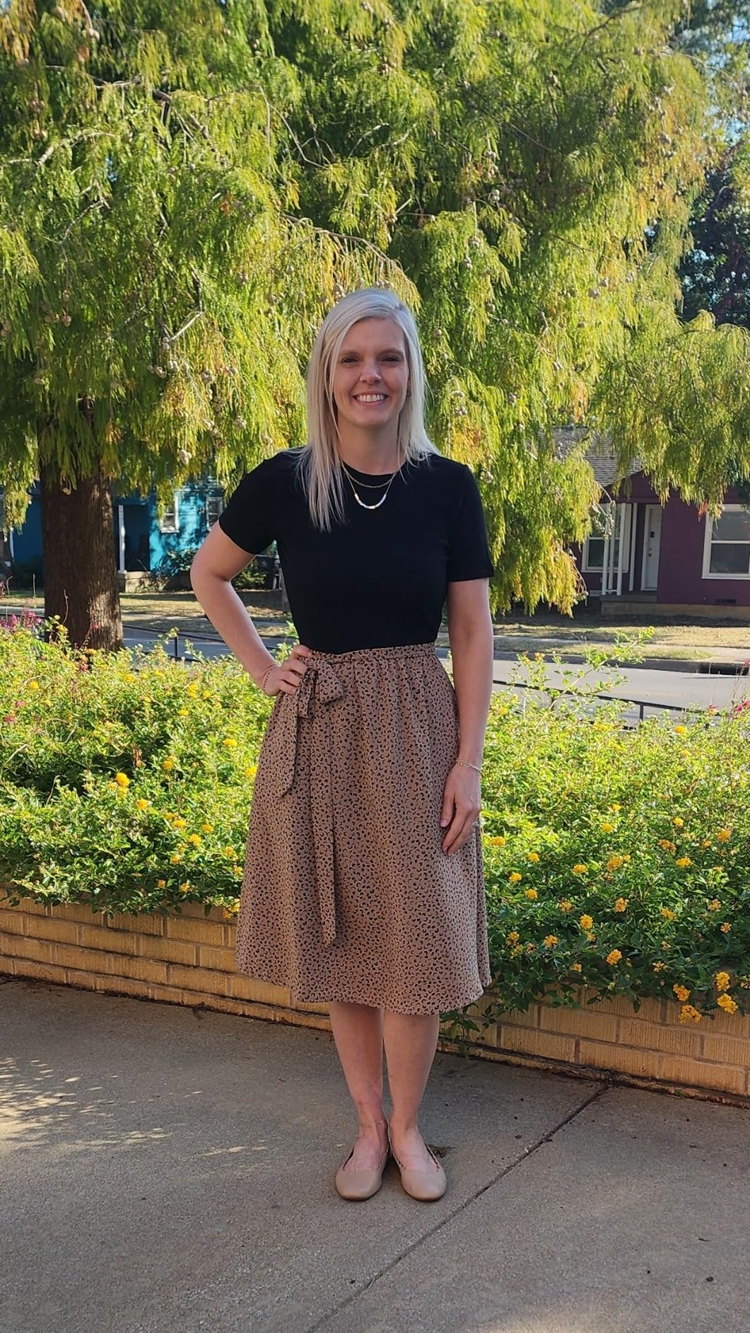  achromatic  top, patterned knee-length skirt, flats, lasting  successful  beforehand   of a plot  with trees successful  the background