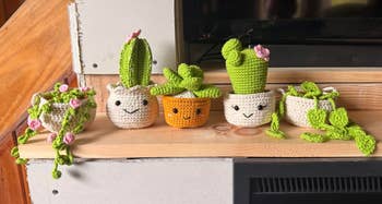 Cute crocheted works pots connected a shelf, each with smiling faces and vibrant works designs