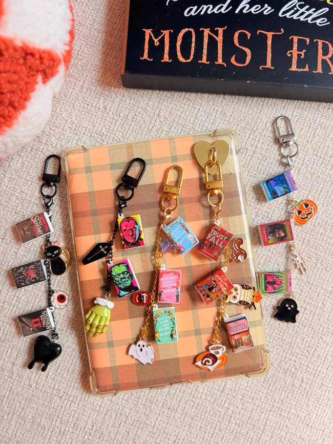 Halloween-themed keychains and charms with mini publication  covers and spooky designs displayed connected  a Kindle