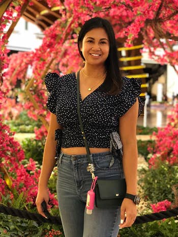 reviewer wearing the black polka dotted top with jeans and a crossbody bag