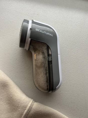 Fabric shaver connected a table, designed for removing lint and fuzz from clothing, featuring a transparent lint container
