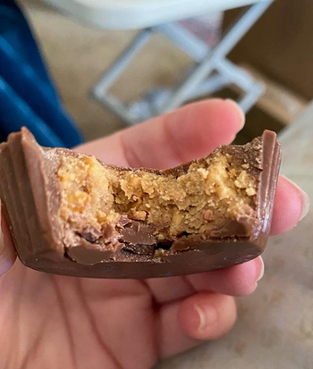 reviewer photo of a half eaten reese's cup to show the thick layer of peanut butter inside