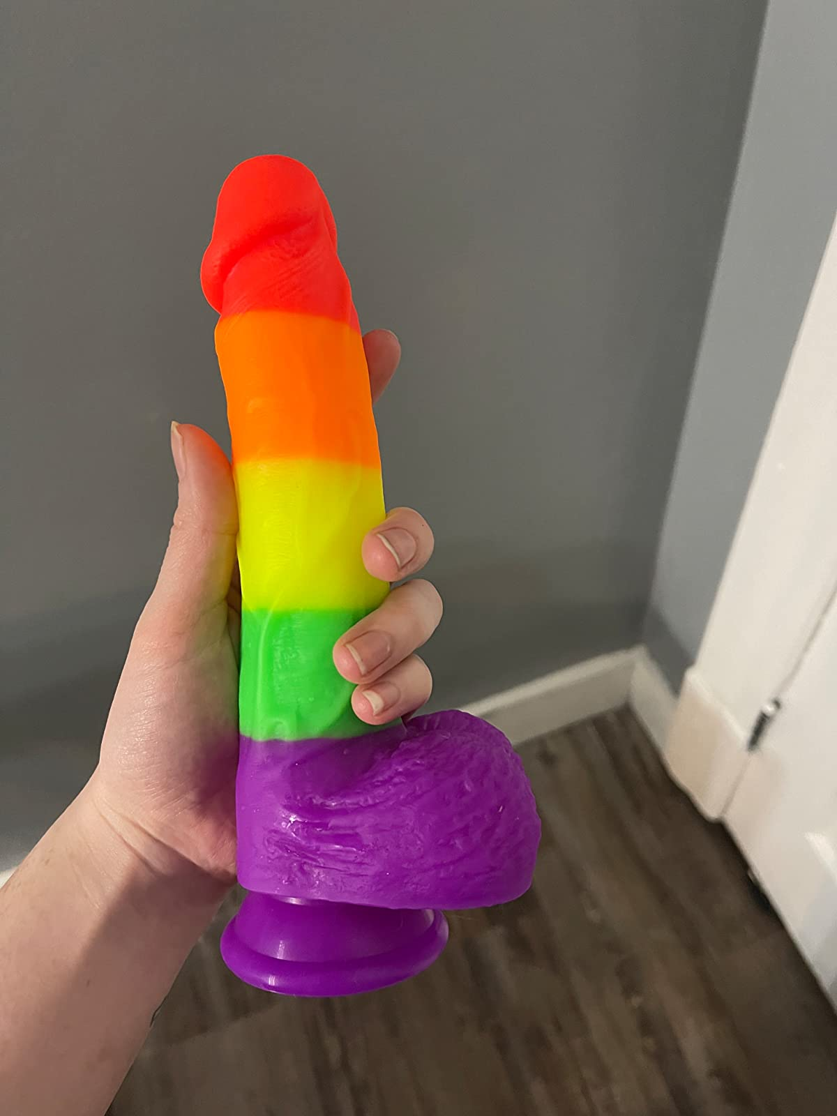 reviewer holding rainbow stripe dildo