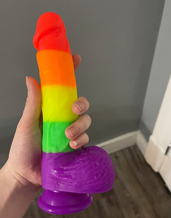 reviewer holding rainbow stripe dildo