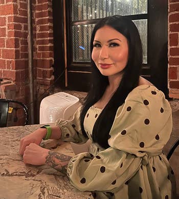 reviewer in polka dot dress sitting at table, smiling