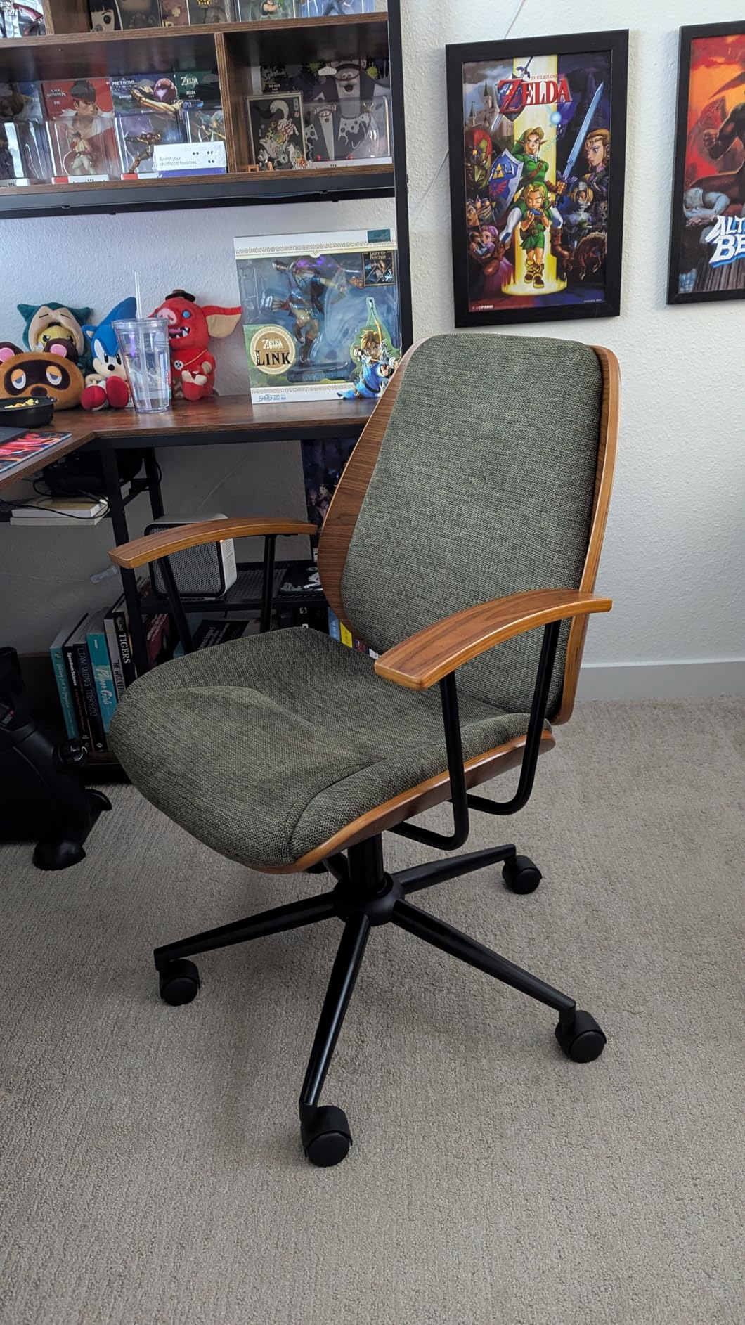 Stylish bureau   seat  with woody  armrests and backrest, grey  cushioned seat, suitable for location  oregon  bureau   setup. Shelves with gaming collectibles successful  the background