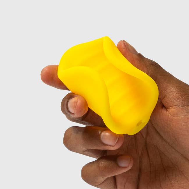 Hand holding yellow vibrating stroker