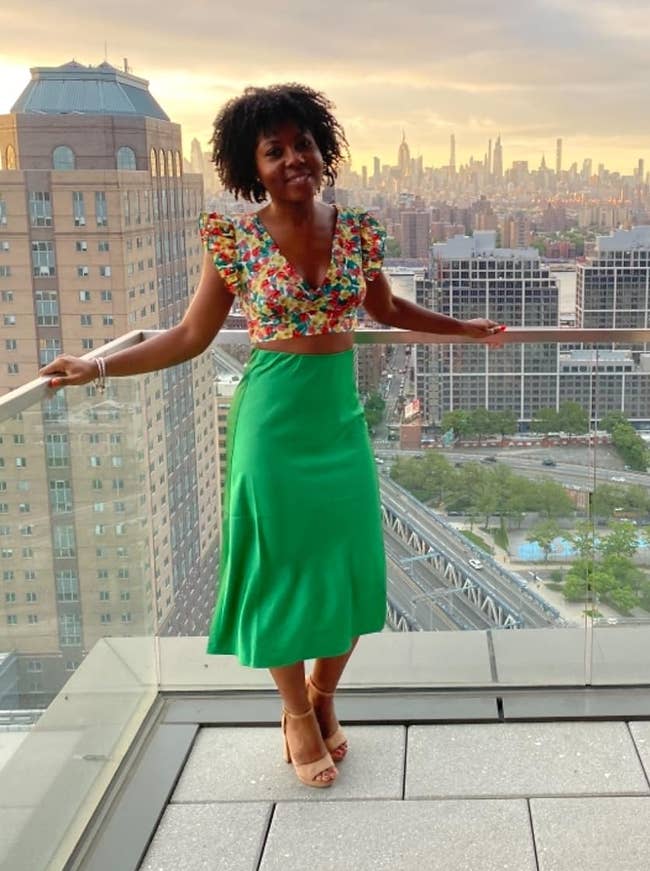 The reviewer wearing a patterned apical and greenish midi skirt connected a balcony implicit looking the city