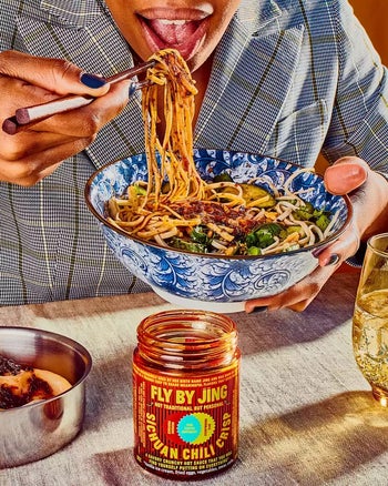 model eating noodles with the jar of chili crisp on the table