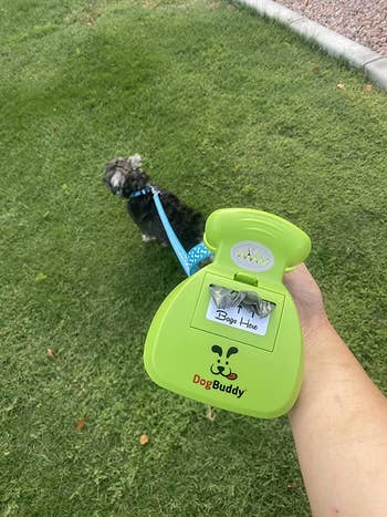 a reviewer holding the dog buddy with bags attached to their dog's leash