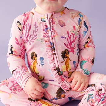 a baby in a pink ruffled little mermaid themed one piece pajama 