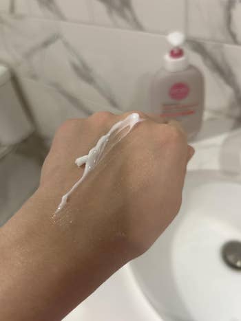 Lotion being applied connected  a manus  implicit    a descend  with a soap dispenser successful  the background, illustrating skincare application