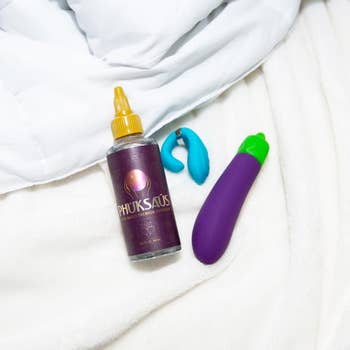 Bottle of Phuksaus water-based lubricant, aqua finger vibrator and purple eggplant emoji vibrator